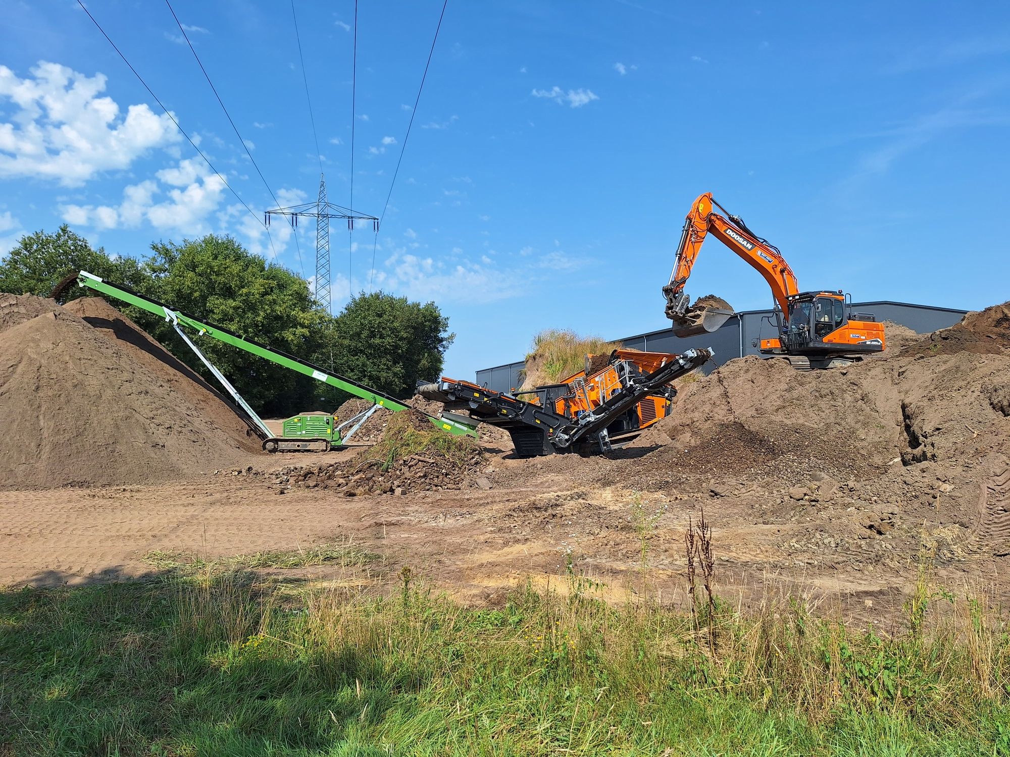 Bagger und Fördermaschinen arbeiten auf einem Erdhügel